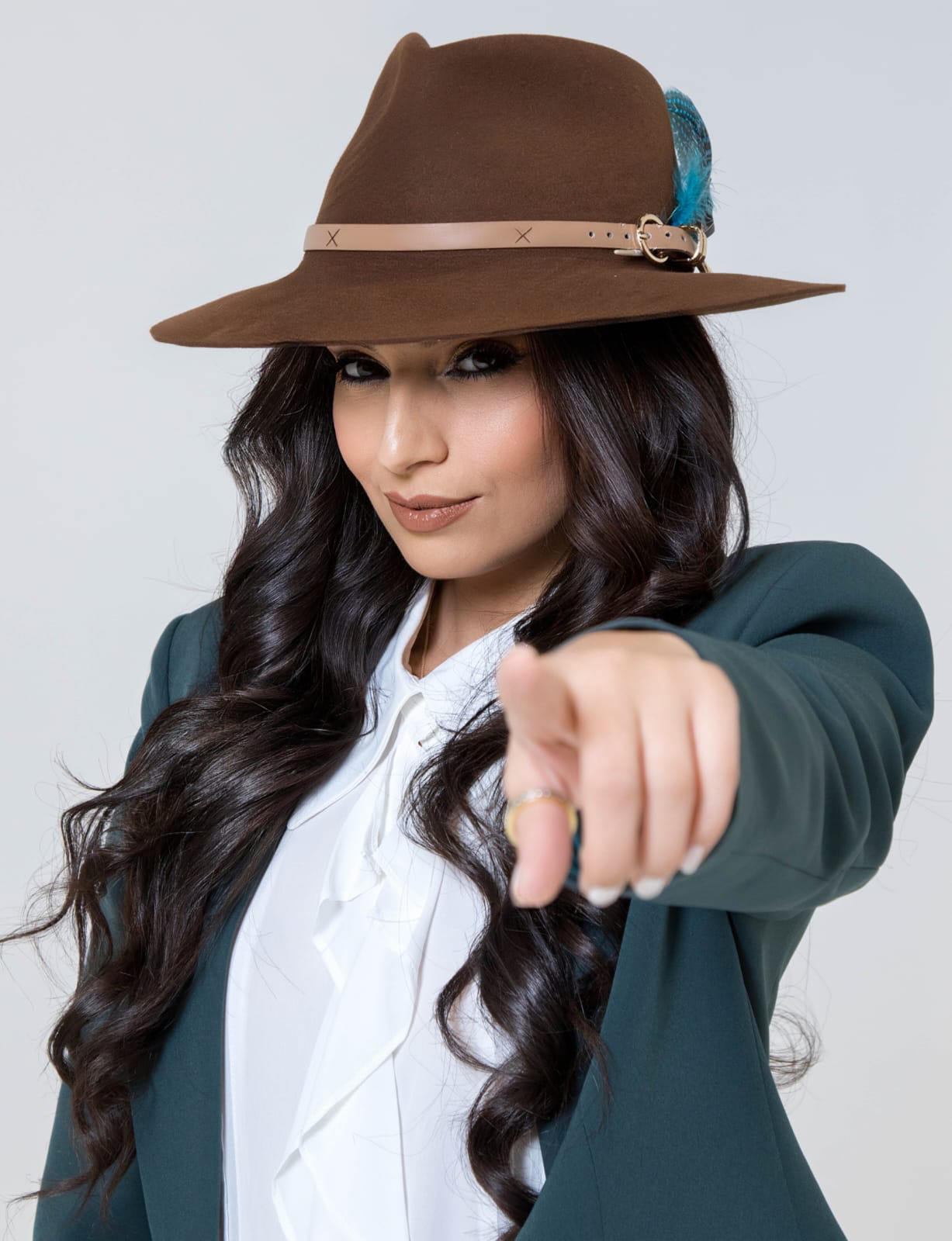 Ghazaleh Ghasemi pointing forward in brown fedora and teal blazer, confident Toronto motivational speaker editorial portrait