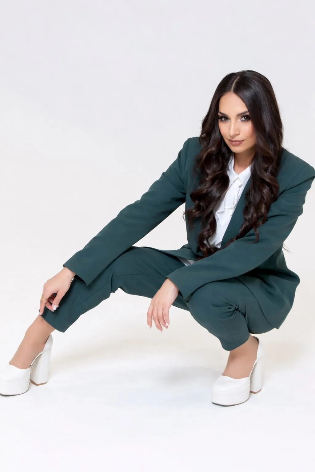 Editorial portrait of Ghazaleh Ghasemi crouching in suit, Persian-Canadian bilingual master of ceremonies and motivational speaker in Toronto