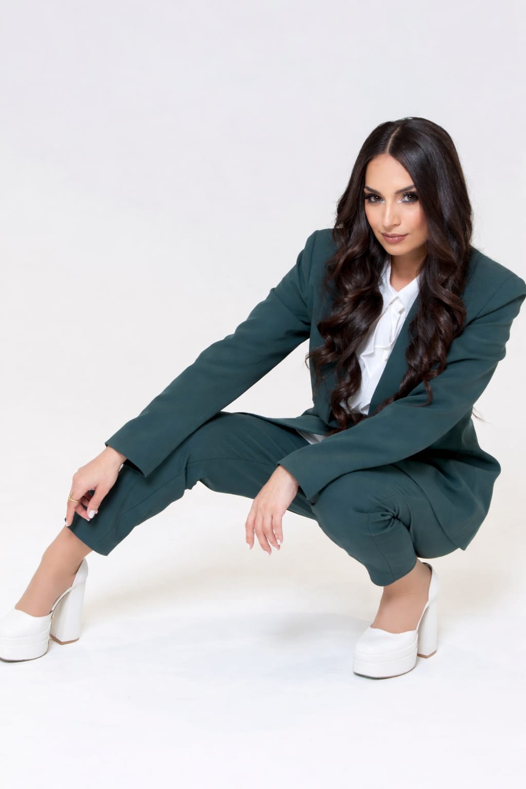 Ghazaleh Ghasemi editorial portrait, Persian-Canadian motivational speaker and event producer, crouching pose in tailored suit
